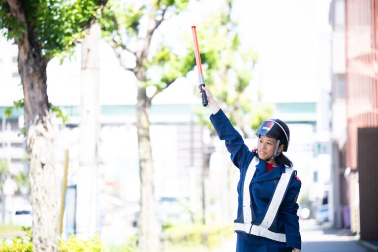 誘導灯を高く掲げる警備員