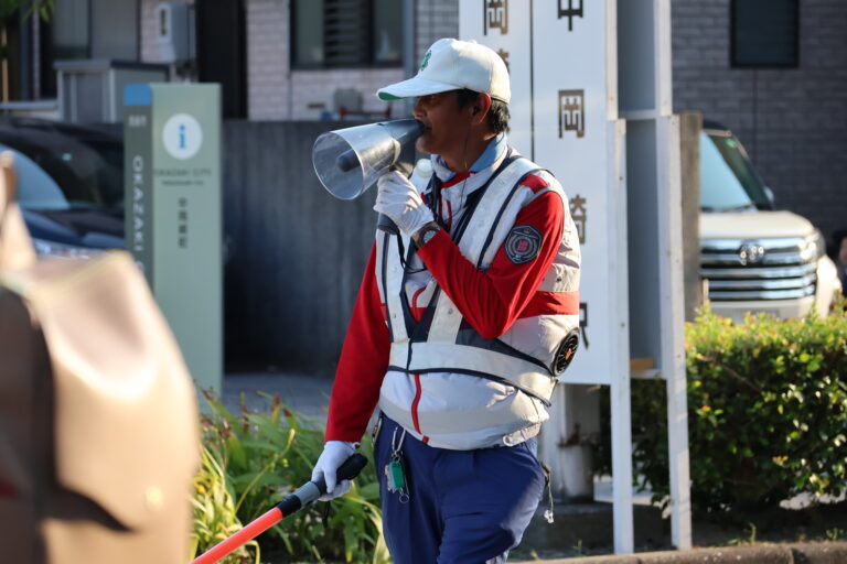 拡声器で案内をする警備員